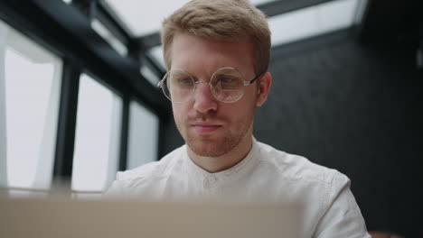 Stilvoller-Mann-Mit-Sehbrille-Arbeitet-Mit-Konzentriertem-Und-Ernstem-Gesicht-Am-Laptop